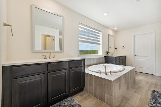 bathroom with tiled bath and vanity