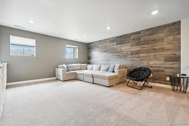 unfurnished living room featuring light carpet, a wealth of natural light, and wooden walls