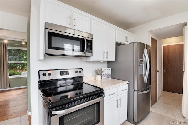 3961 S Uravan St, Aurora, CO 80013 - kitchen with appliances with stainless steel finishes, light countertops, white cabinetry, light tile patterned floors, and baseboards