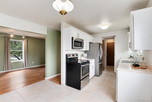 3961 S Uravan St, Aurora, CO 80013 - kitchen featuring stainless steel appliances, light countertops, a sink, white cabinetry, and light tile patterned floors