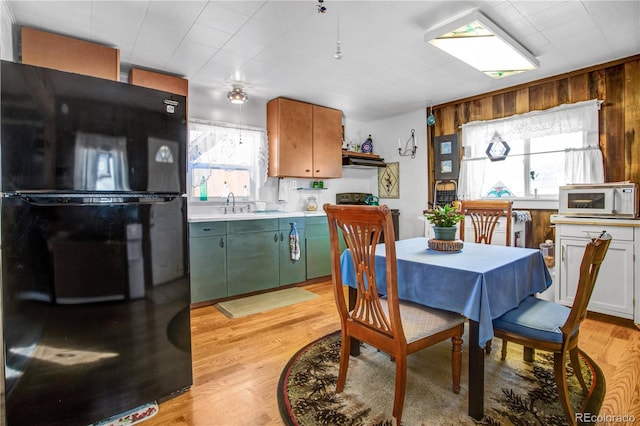 kitchen featuring black fridge, white cabinetry, plenty of natural light, and light hardwood / wood-style flooring