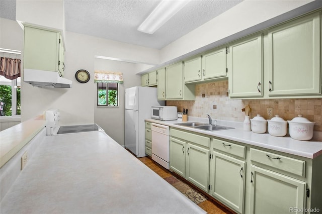 kitchen with backsplash, green cabinets, sink, and white appliances