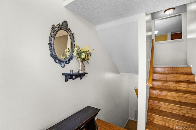 stairs featuring vaulted ceiling and a textured ceiling