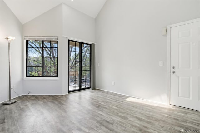 unfurnished room featuring high vaulted ceiling and wood finished floors