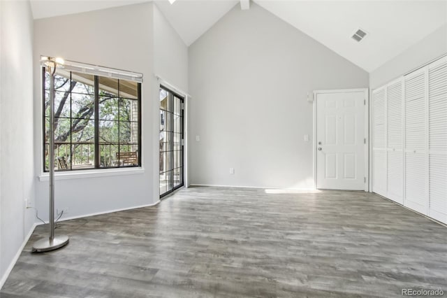 unfurnished bedroom featuring high vaulted ceiling, wood finished floors, baseboards, access to outside, and a closet