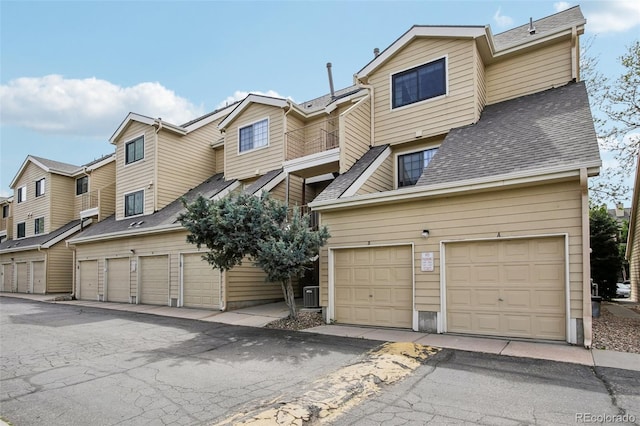 multi unit property featuring community garages, a shingled roof, and a residential view