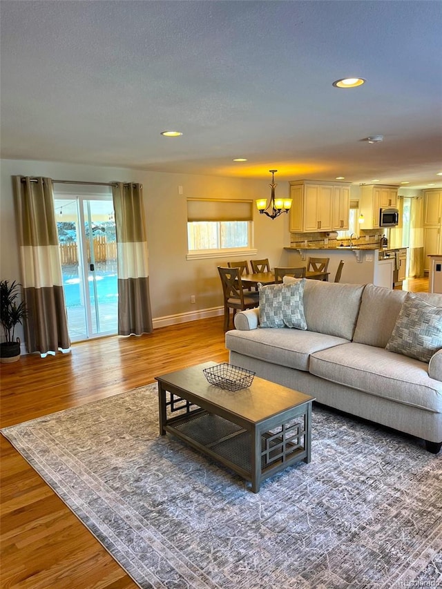 living room with a healthy amount of sunlight, a chandelier, and hardwood / wood-style flooring