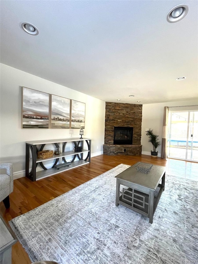 living room featuring a stone fireplace and hardwood / wood-style floors