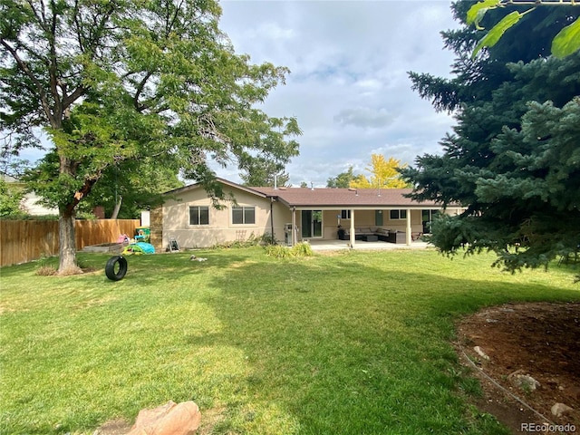 back of property featuring a patio area, a lawn, and an outdoor living space