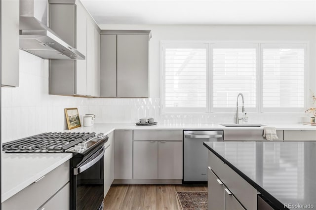 15006 Cast Pebble Cir, Parker, CO 80134 - kitchen with stainless steel appliances, gray cabinets, wall chimney exhaust hood, light wood-style floors, and decorative backsplash