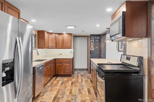 55 Two Moon Rd, Idaho Springs, CO 80452 - kitchen with stainless steel appliances, light wood-style floors, brown cabinets, decorative backsplash, and recessed lighting