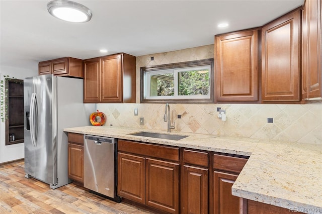 55 Two Moon Rd, Idaho Springs, CO 80452 - kitchen with stainless steel appliances, light wood-type flooring, tasteful backsplash, brown cabinetry, and light stone counters