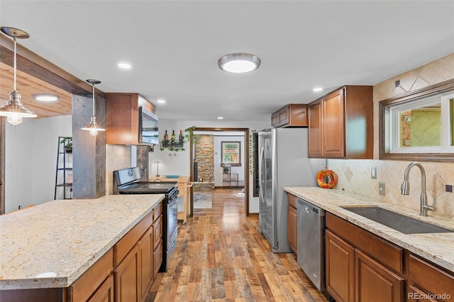 55 Two Moon Rd, Idaho Springs, CO 80452 - kitchen featuring stainless steel appliances, light wood-style flooring, brown cabinetry, light stone countertops, and backsplash