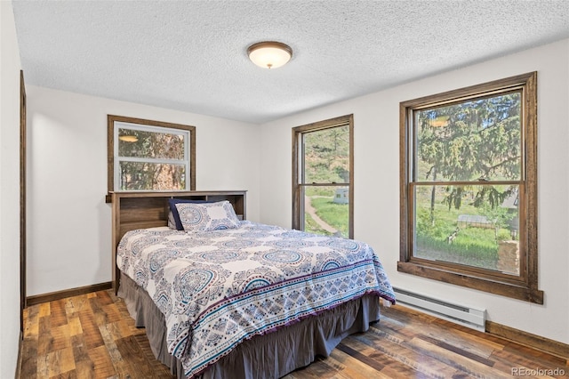 55 Two Moon Rd, Idaho Springs, CO 80452 - bedroom featuring a baseboard heating unit, wood finished floors, and a textured ceiling