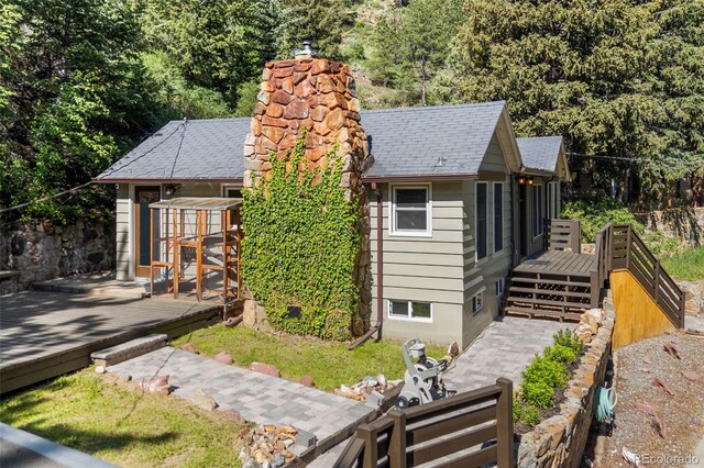 55 Two Moon Rd, Idaho Springs, CO 80452 - view of front facade featuring a deck, a chimney, an outbuilding, and roof with shingles