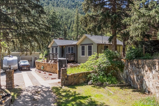55 Two Moon Rd, Idaho Springs, CO 80452 - ranch-style house featuring driveway, a forest view, an attached garage, and a deck
