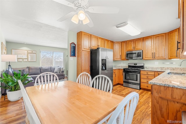 kitchen with light wood-type flooring, brown cabinetry, stainless steel appliances, and a sink