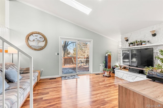 living area featuring a skylight, light wood finished floors, visible vents, high vaulted ceiling, and baseboards