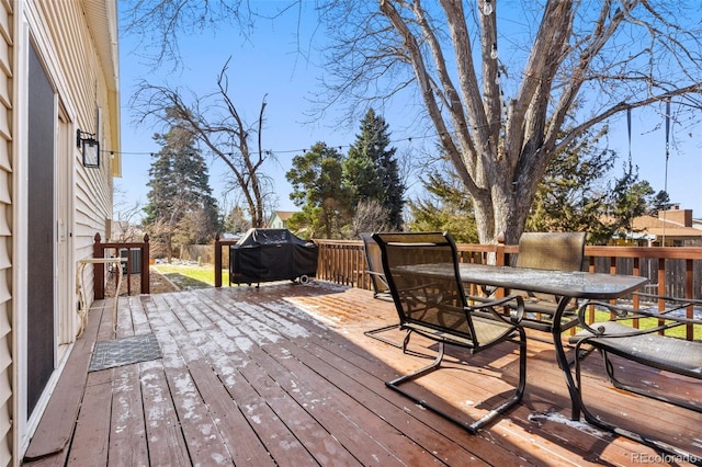 wooden deck featuring a grill and outdoor dining space