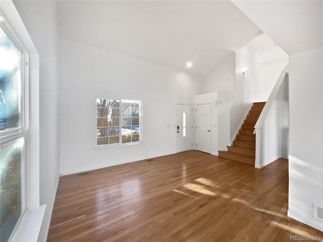 unfurnished living room featuring high vaulted ceiling and dark hardwood / wood-style flooring