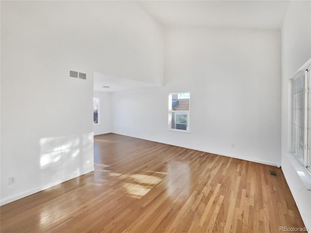 unfurnished living room featuring hardwood / wood-style flooring and a towering ceiling