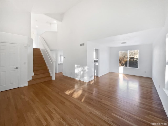 unfurnished living room featuring hardwood / wood-style flooring and a towering ceiling