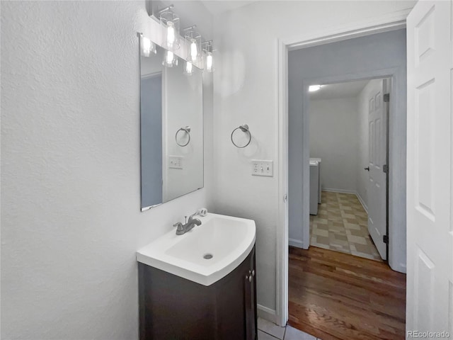 bathroom with hardwood / wood-style flooring, vanity, and washer / dryer