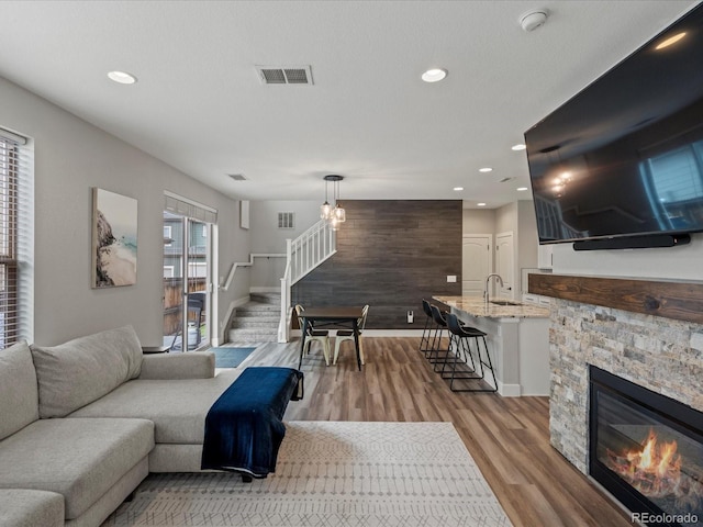 14823 W 70th Dr Unit A, Arvada, CO 80007 - living area featuring stairs, light wood-style floors, a stone fireplace, recessed lighting, and baseboards