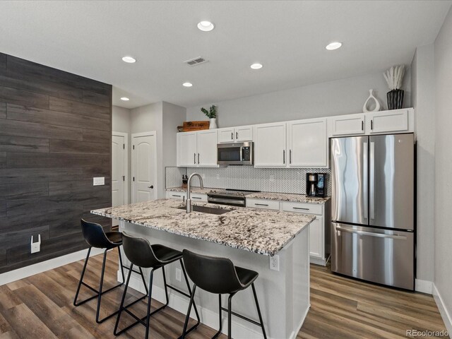 14823 W 70th Dr Unit A, Arvada, CO 80007 - kitchen featuring stainless steel appliances, a sink, white cabinetry, a center island with sink, and dark wood-style floors