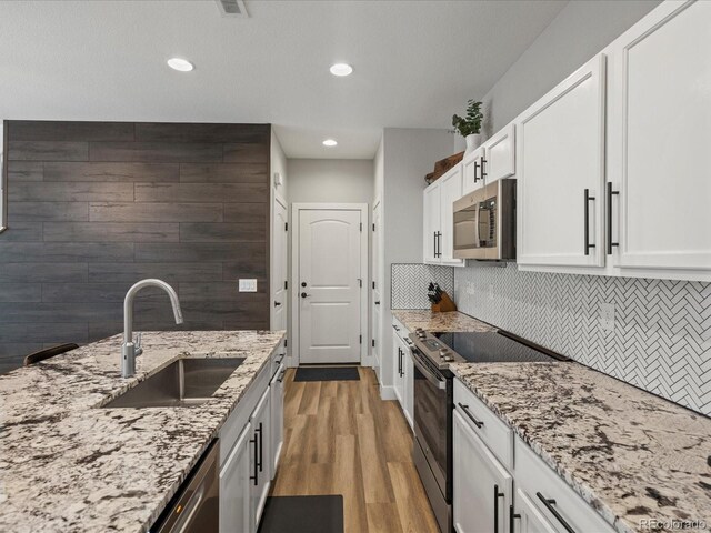 14823 W 70th Dr Unit A, Arvada, CO 80007 - kitchen featuring appliances with stainless steel finishes, a sink, white cabinetry, light stone countertops, and tasteful backsplash