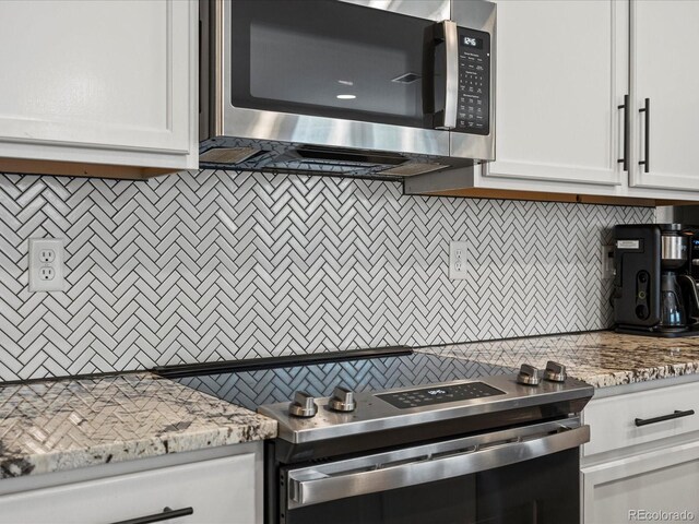 14823 W 70th Dr Unit A, Arvada, CO 80007 - kitchen featuring stainless steel appliances, white cabinetry, decorative backsplash, and light stone countertops