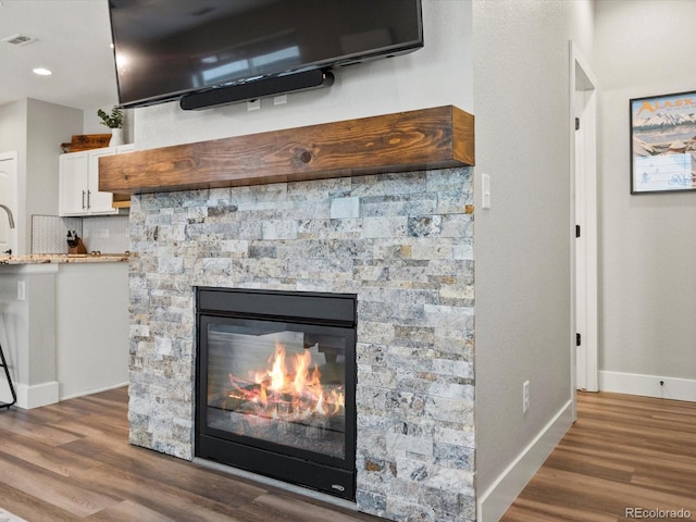 14823 W 70th Dr Unit A, Arvada, CO 80007 - detailed view of wood finished floors, a stone fireplace, baseboards, and backsplash