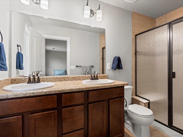 14823 W 70th Dr Unit A, Arvada, CO 80007 - bathroom featuring a shower stall, ensuite bathroom, double vanity, toilet, and tile patterned floors