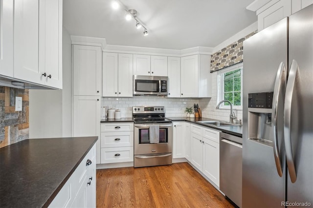 6880 E Appleton Cir, Centennial, CO 80112 - kitchen featuring stainless steel appliances, a sink, dark countertops, white cabinets, and backsplash