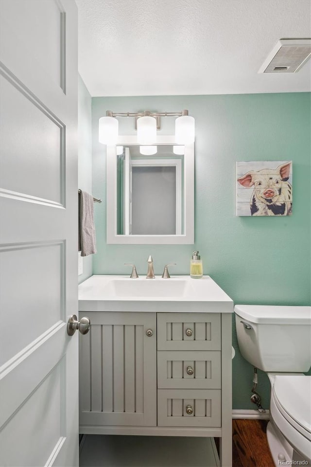 6880 E Appleton Cir, Centennial, CO 80112 - half bath featuring toilet, vanity, a textured ceiling, wood finished floors, and baseboards
