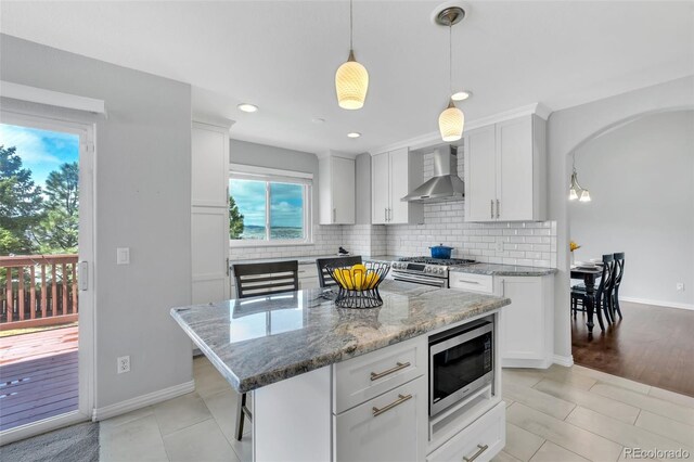16655 W 2nd Ave, Golden, CO 80401 - kitchen with backsplash, wall chimney exhaust hood, appliances with stainless steel finishes, and white cabinetry