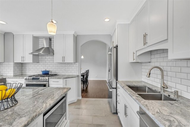 16655 W 2nd Ave, Golden, CO 80401 - kitchen with recessed lighting, stainless steel appliances, wall chimney range hood, a sink, and arched walkways