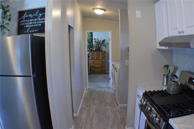 kitchen featuring a textured ceiling, under cabinet range hood, white cabinetry, appliances with stainless steel finishes, and washer / clothes dryer