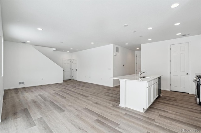 kitchen featuring a kitchen island with sink, sink, white cabinets, and light hardwood / wood-style flooring