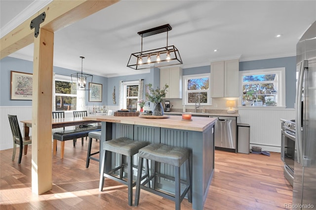 kitchen with white cabinetry, butcher block countertops, a breakfast bar area, decorative light fixtures, and a center island