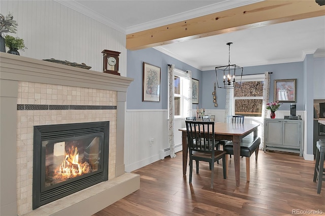 dining area featuring baseboard heating, hardwood / wood-style floors, crown molding, and a notable chandelier