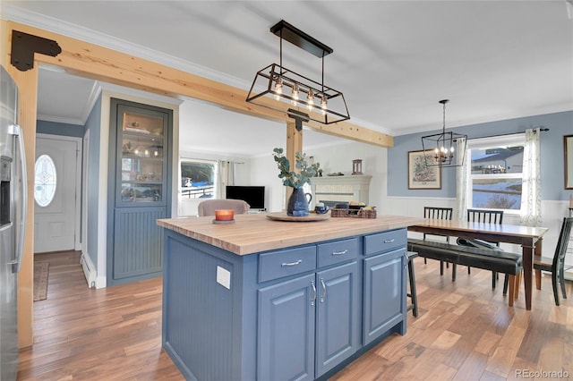 kitchen with wood counters, blue cabinetry, a kitchen island, pendant lighting, and a breakfast bar