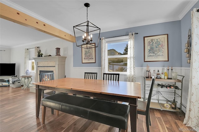 dining room with hardwood / wood-style floors, a tile fireplace, crown molding, and a chandelier