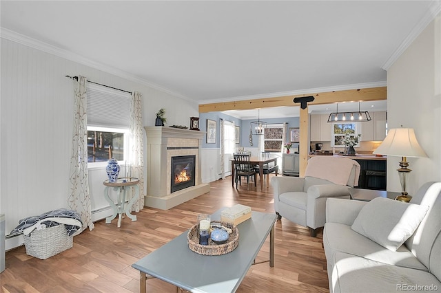 living room featuring light hardwood / wood-style floors, a baseboard radiator, crown molding, and a tiled fireplace