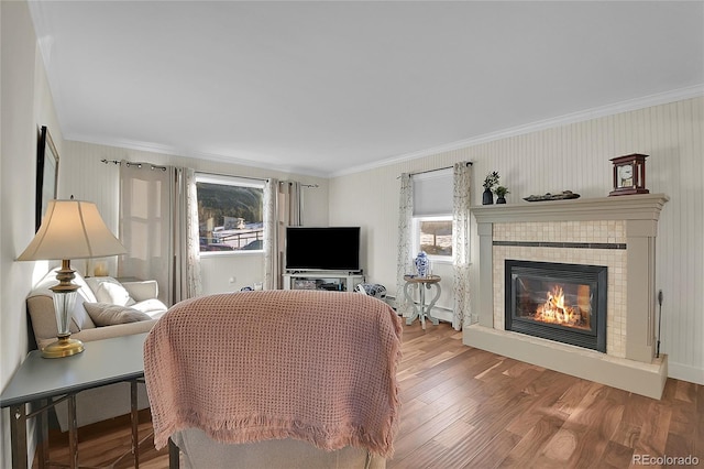 living room with ornamental molding, hardwood / wood-style floors, a tile fireplace, and a baseboard radiator