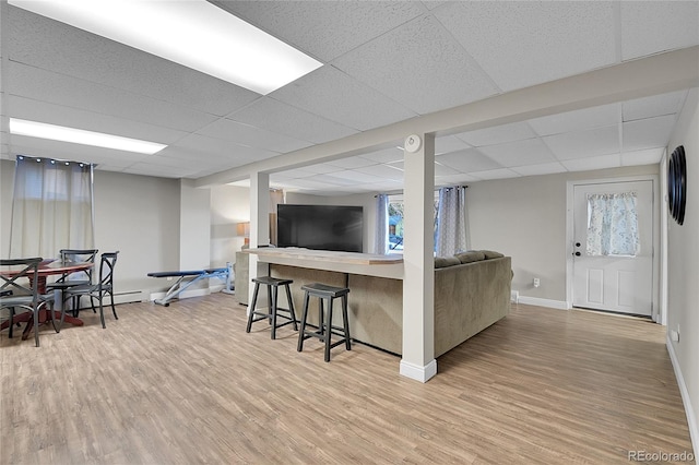 living room with light hardwood / wood-style floors and a drop ceiling