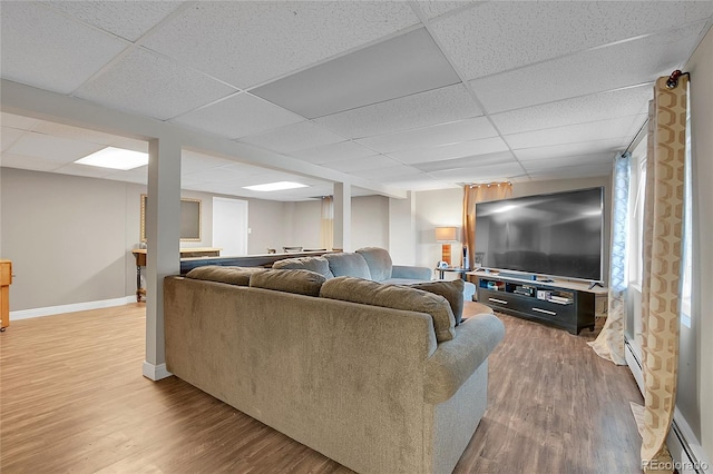 living room with a paneled ceiling, baseboard heating, and hardwood / wood-style flooring