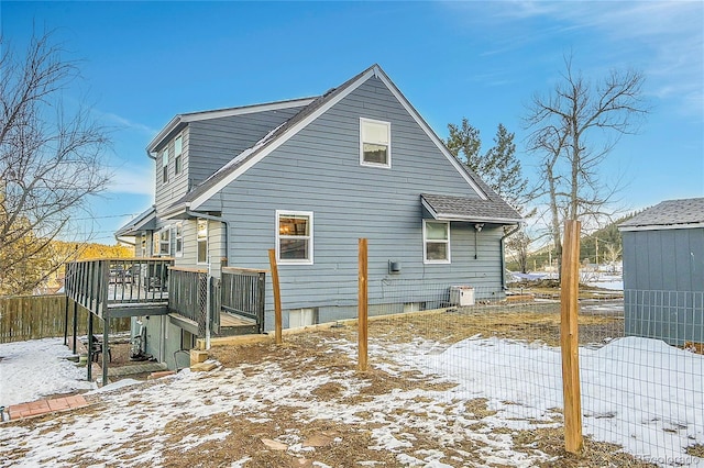 snow covered back of property with a wooden deck