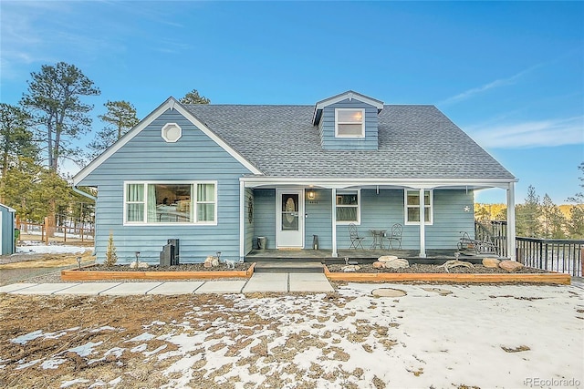 view of front of property with a shingled roof, covered porch, and fence