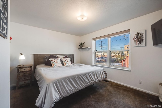 bedroom with a textured ceiling and dark carpet